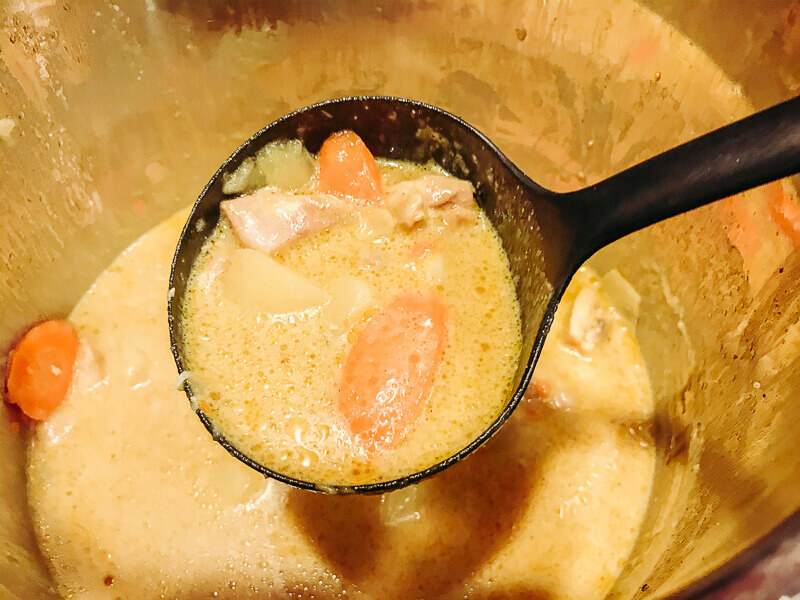 A ladle full of chicken curry inside instant pot.