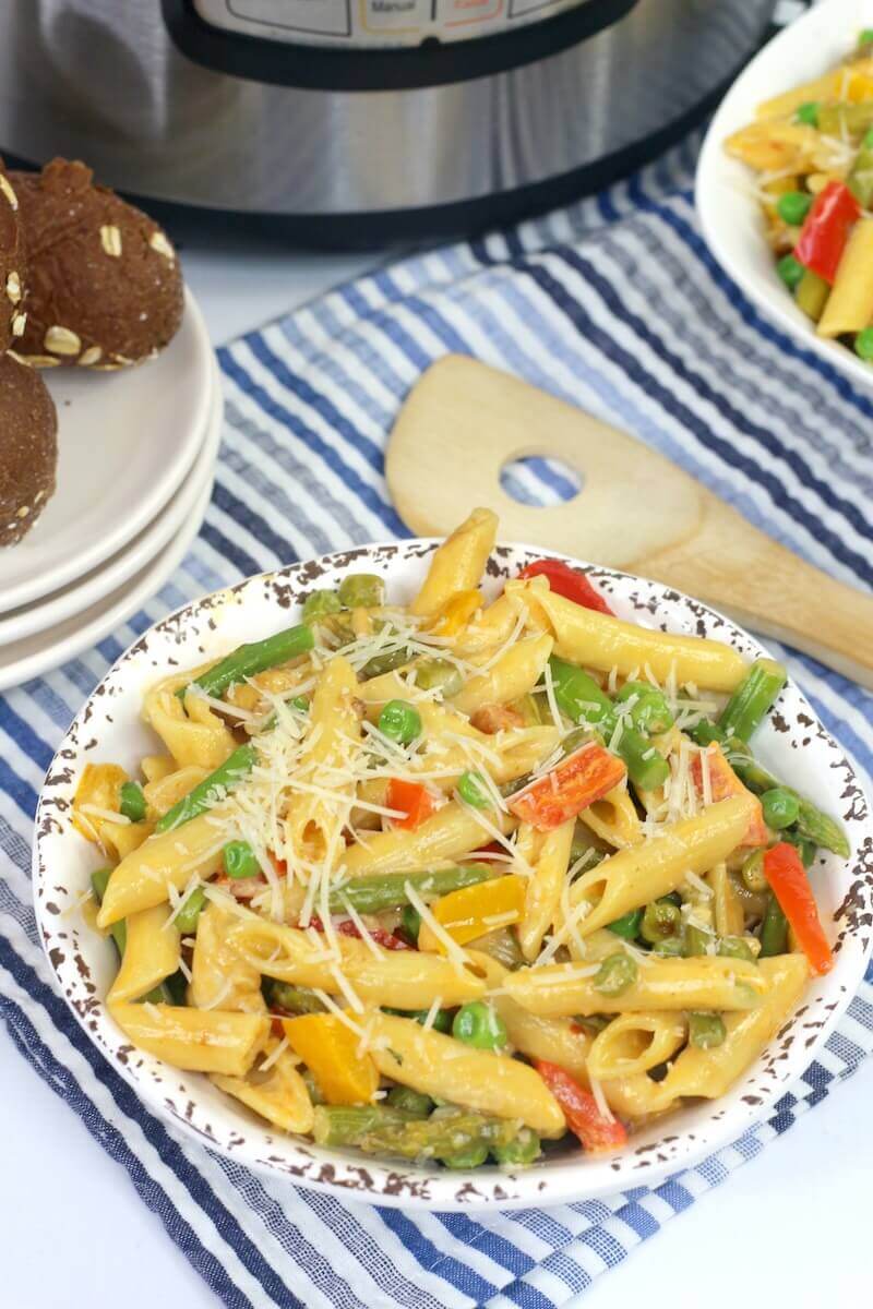 A bowl of chicken pasta over a blue striped towel.