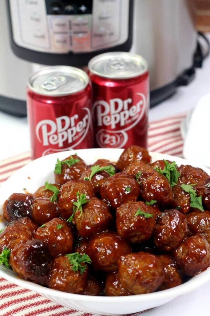 An instant pot with a bowl of meatballs and two cans of dr. pepper in front of it.