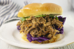 A pulled pork sandwich piled high with red cabbage and lettuce.