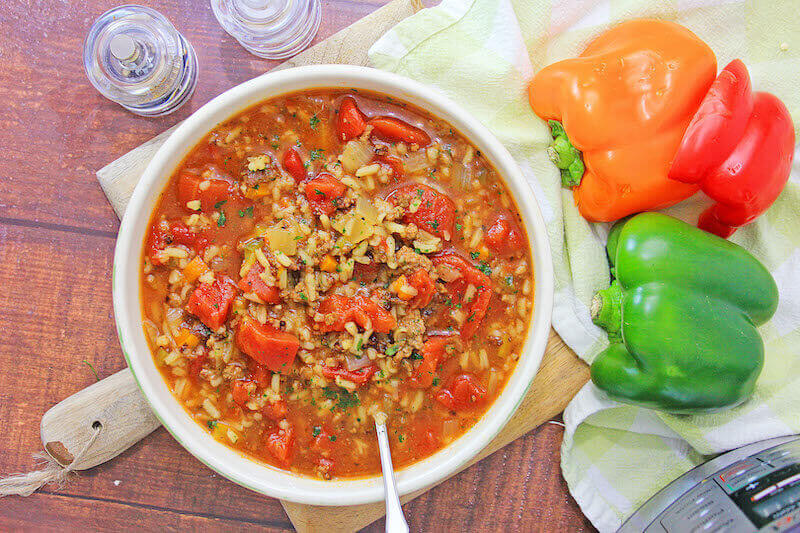 Overhead shot of intant pot stuffed pepper soup next to whole bell peppers.