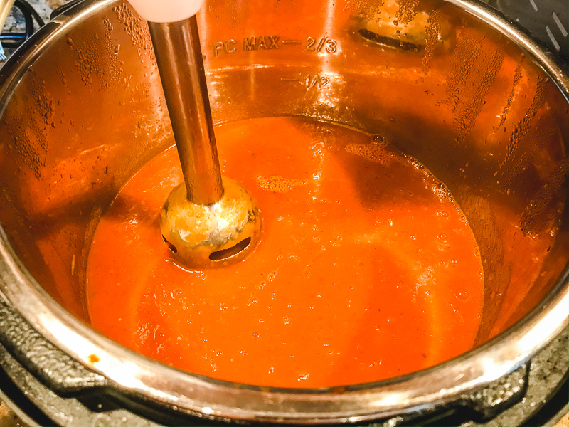 Soup being blended with immersion blender.
