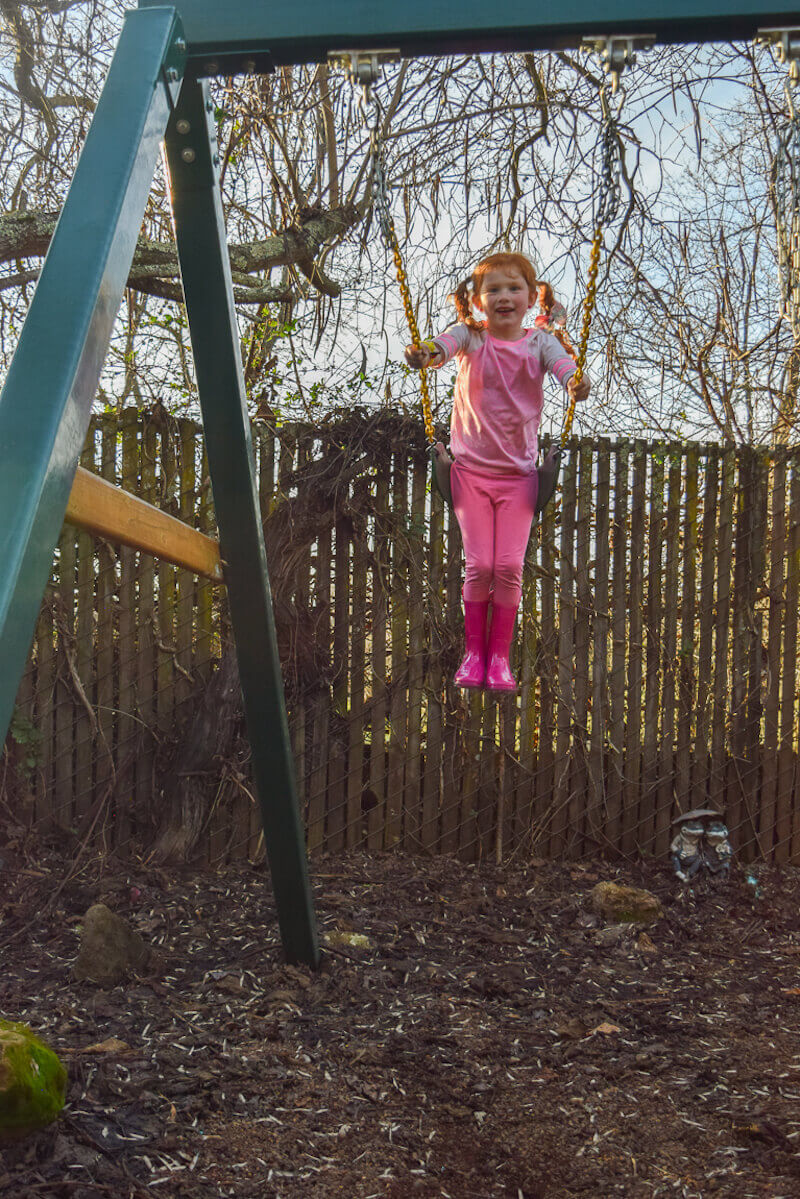 Little girl swinging and smiling.