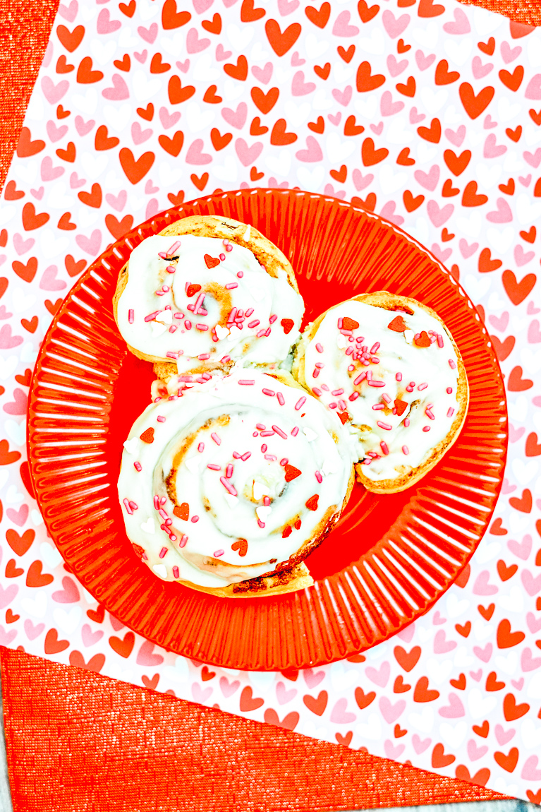 A red plate filled with Valentine's Day-themed Mickey Mouse Cinnamon Rolls.