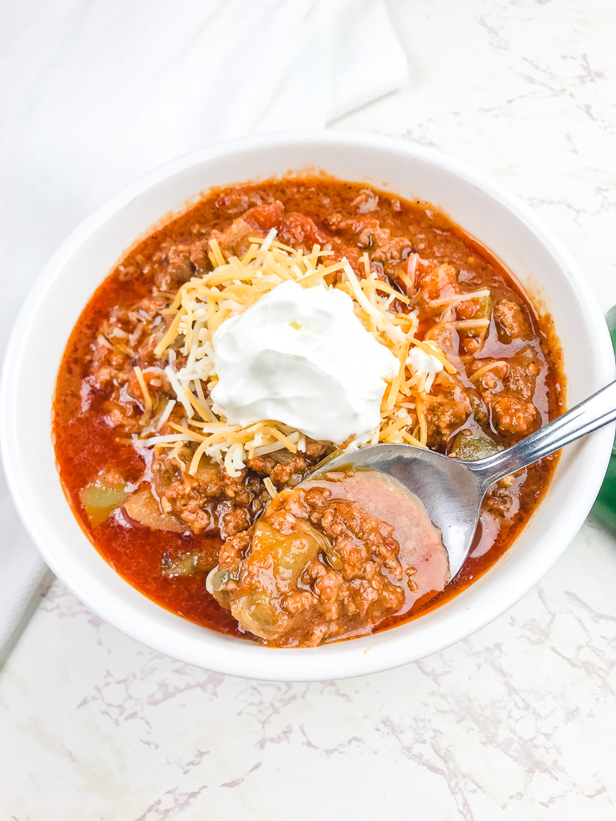 A white bowl filled with no bean chili and topped with a dollop of sour cream.