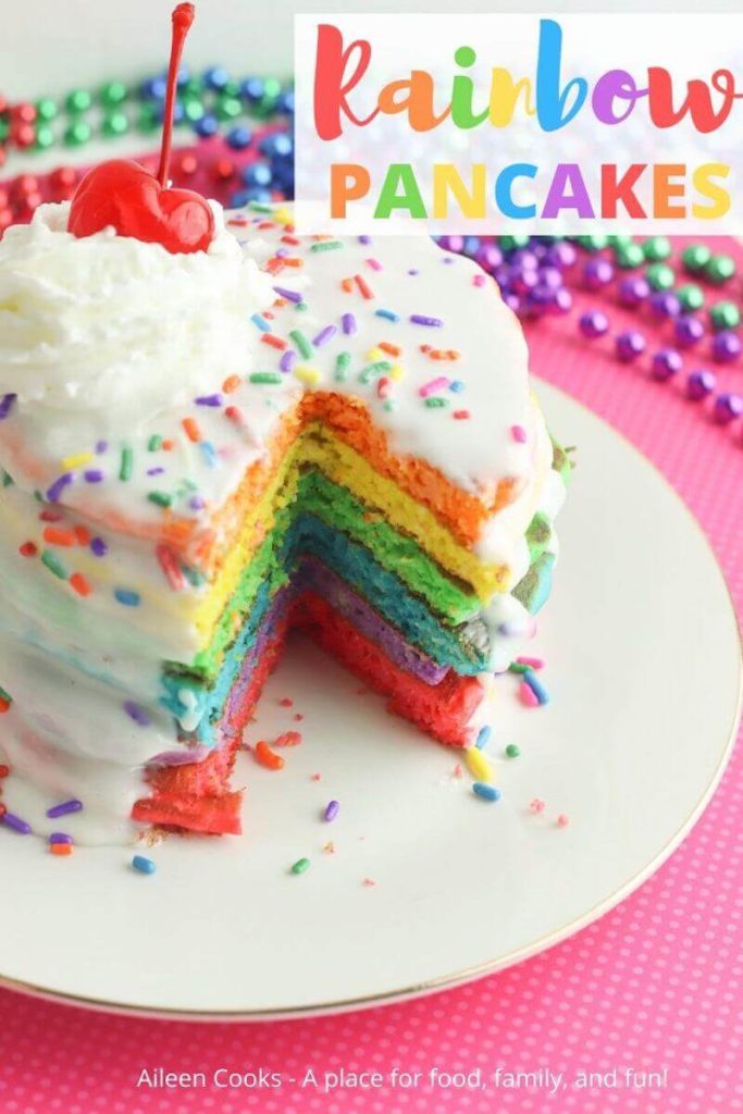 Close up of a stack of colored pancakes with colorful beads in the background.