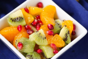 Square serving dish filled with fruit salad with blue tablecloth in the background