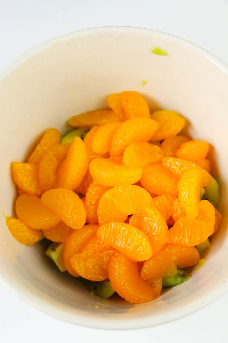 bowl of kiwi topped with mandarin oranges.