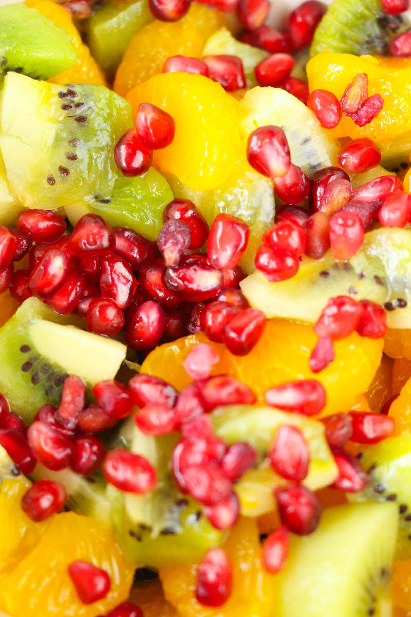 Close up of winter fruit salad made of kiwi, clementines, and pomegranate seeds.