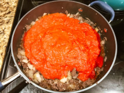 Sauce poured over browned ground beef.