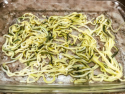 Zucchini noodles in a glass casserole dish.