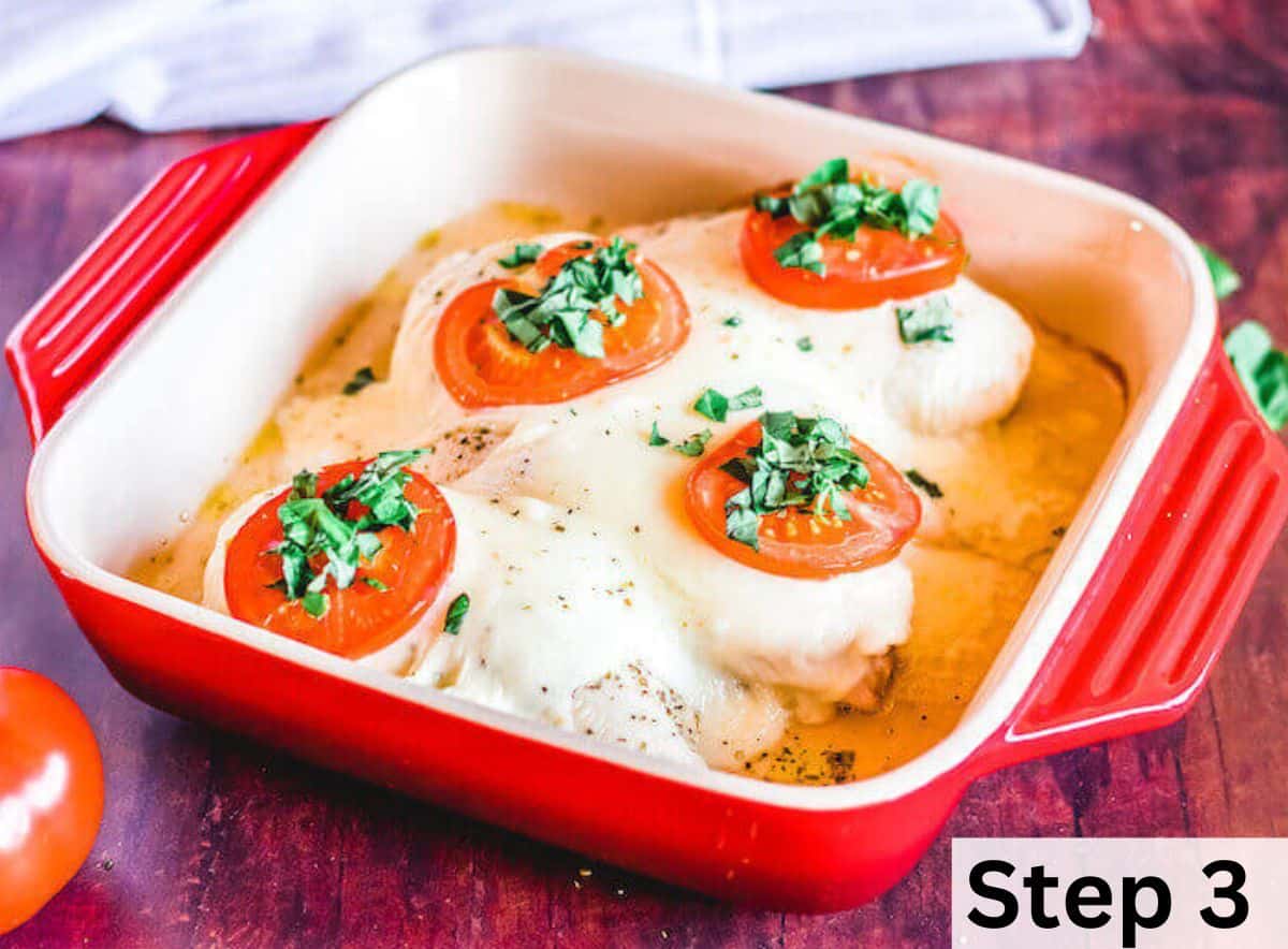 Baked chicken topped with melted cheese, tomato slices, and basil leaves. 