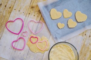 Dough cut into hearts on parchment paper and on cookie sheet.