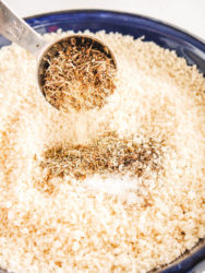 A spoon of seasoning mixing into a bowl of breadcrumbs.