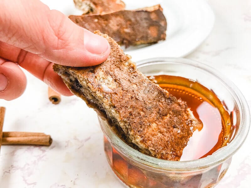 A French toast stick dipped into maple syrup.
