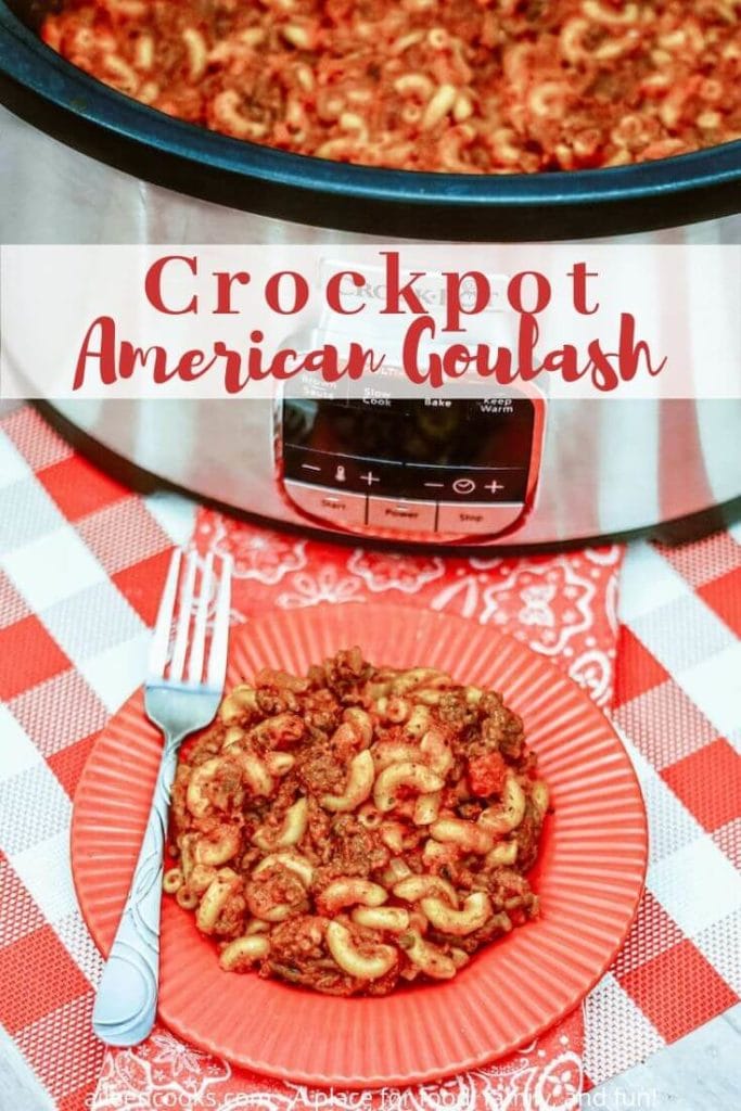 A crockpot with the lid off and filled with meat and pasta behind a red plate of goulash and a fork.