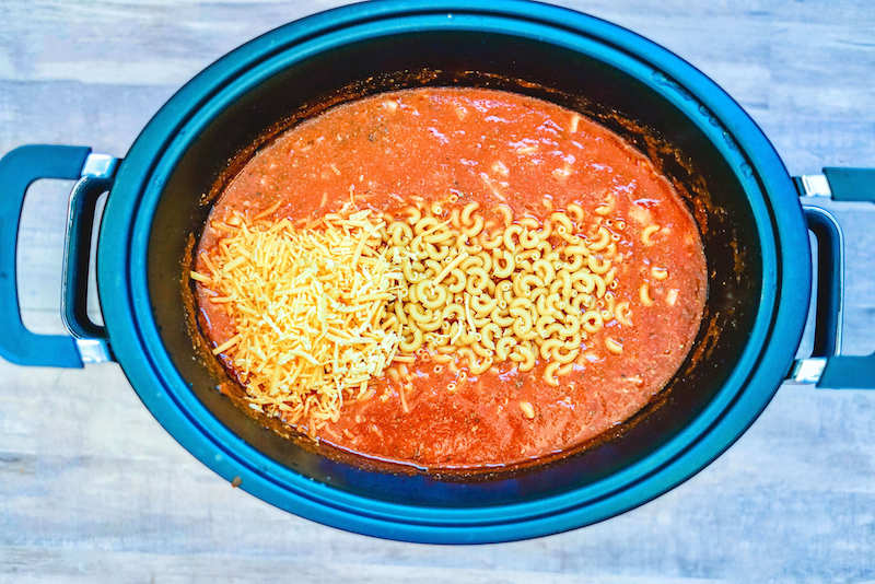 Goulash in the crockpot with cheese and pasta on top.