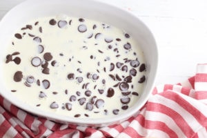 Cream over chocolate chips in white dish.