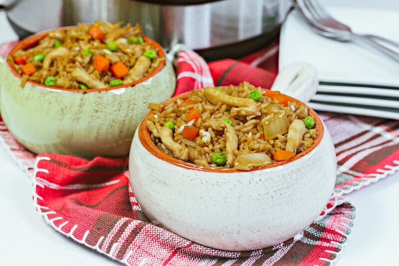 Two white bowls filled with chicken fried rice in front of an instant pot.