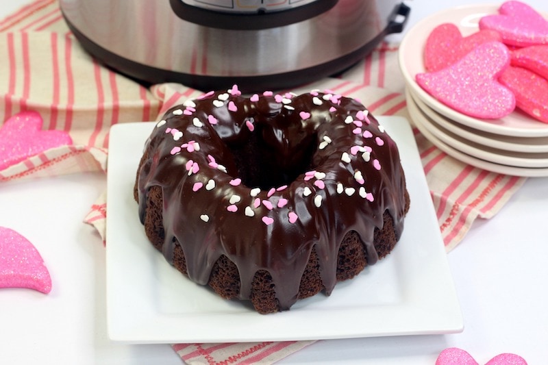A white plate with a heart shaped chocolate cake next to a plate full of pink hearts.