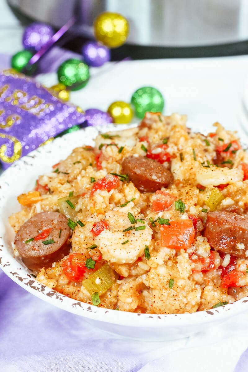 Close up of jambalaya in a white dish with sausages on top.