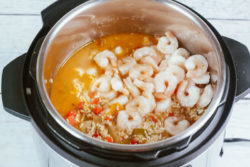 Instant pot filled with cooked jambalaya and shrimp on top.