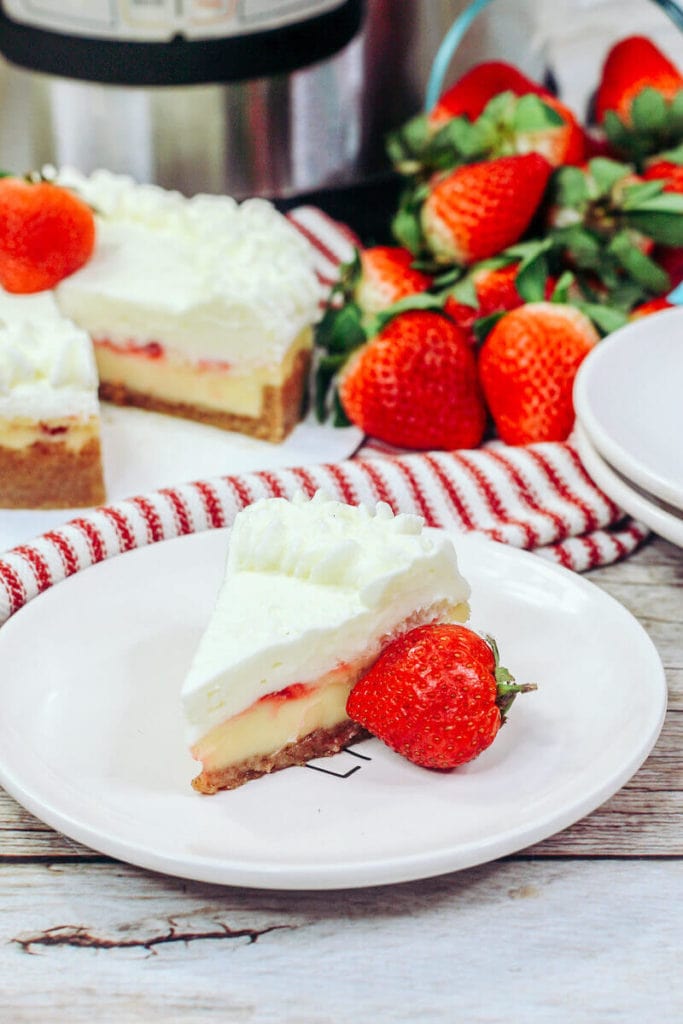 Overhead shot of a slice of strawberry cheesecake next to the whole cheesecake.