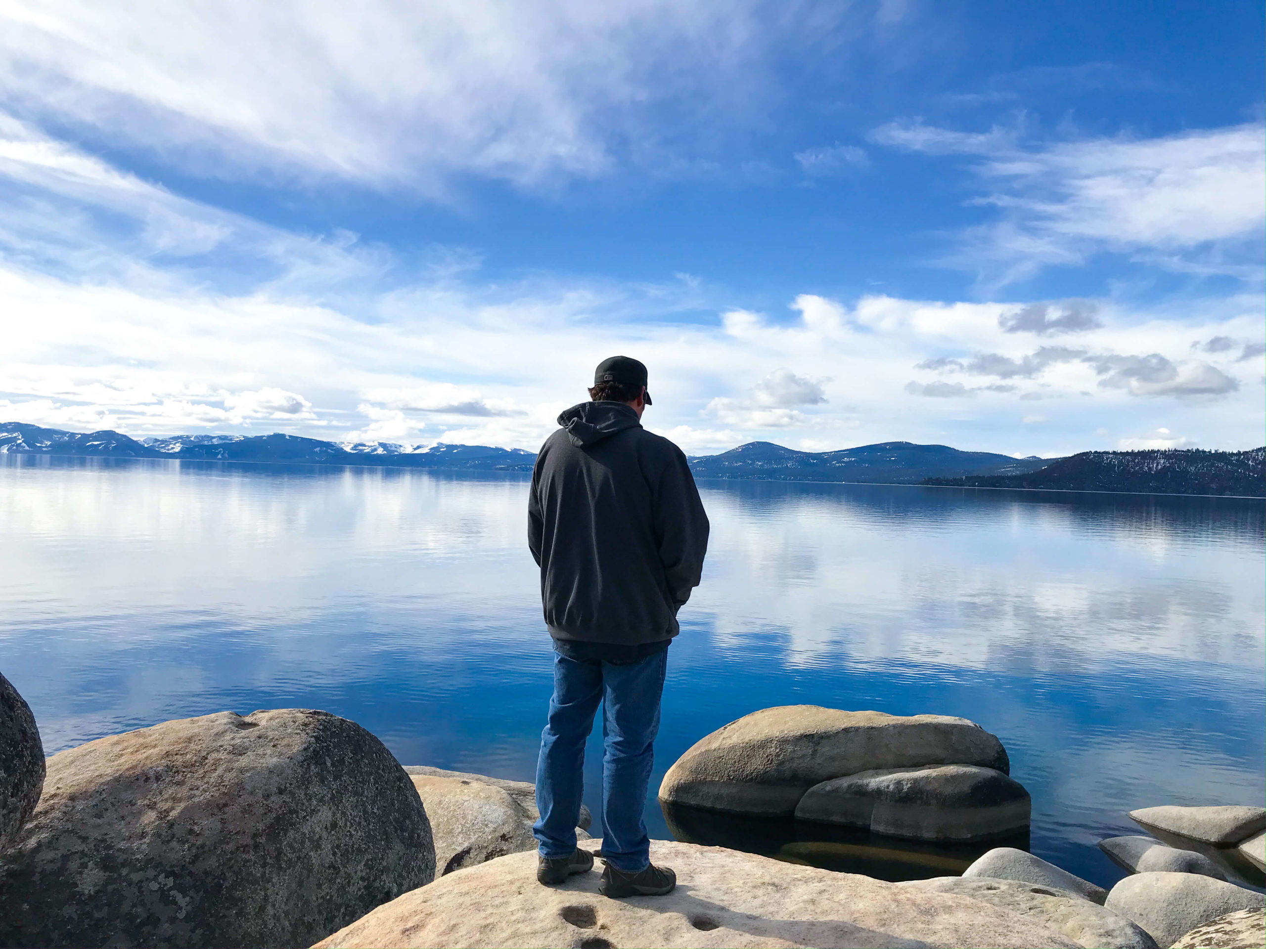 A man standing on a rock in front of Lake Tahoe.