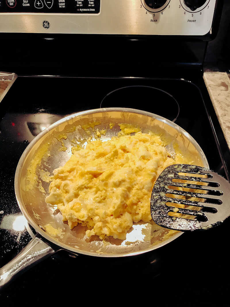 A pan full of scrambled eggs on an electric stove top.