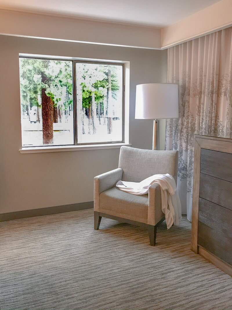 A sitting chair next to a window with views of the snowy landscape.