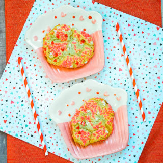 Two cupcake shaped plates with valentine's sprinkle cookies on them.