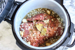 Corned beef topped with garlic and bay leaf inside Ninja Foodi cock pot.