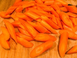 Cut up carrots on a wooden cutting board.