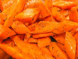 Close up of carrots evenly coated with oil, herbs, and spices.