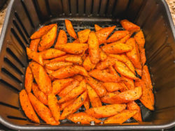 Air fried carrots inside of black air fryer basket.