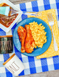 Blue and white checkered placemat topped with a blue plate of bbq air fryer drumsticks.