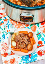A plate of roast beef in front of a crockpot.