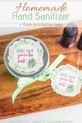 Overhead shot of jar of hand sanitizer with gift tag and green ribbon.