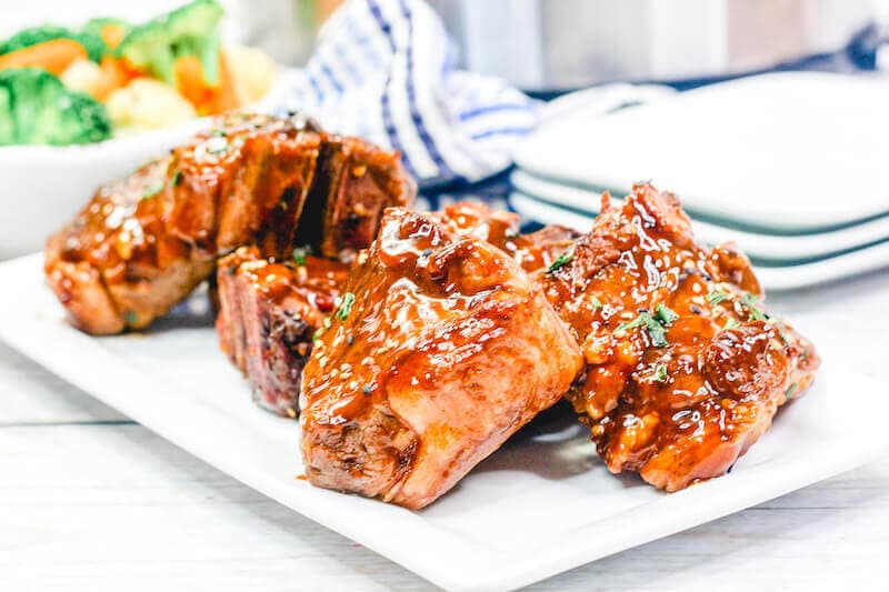 Sticky lamb chops on a white platter.