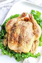 A whole chicken on a bed of lettuce.