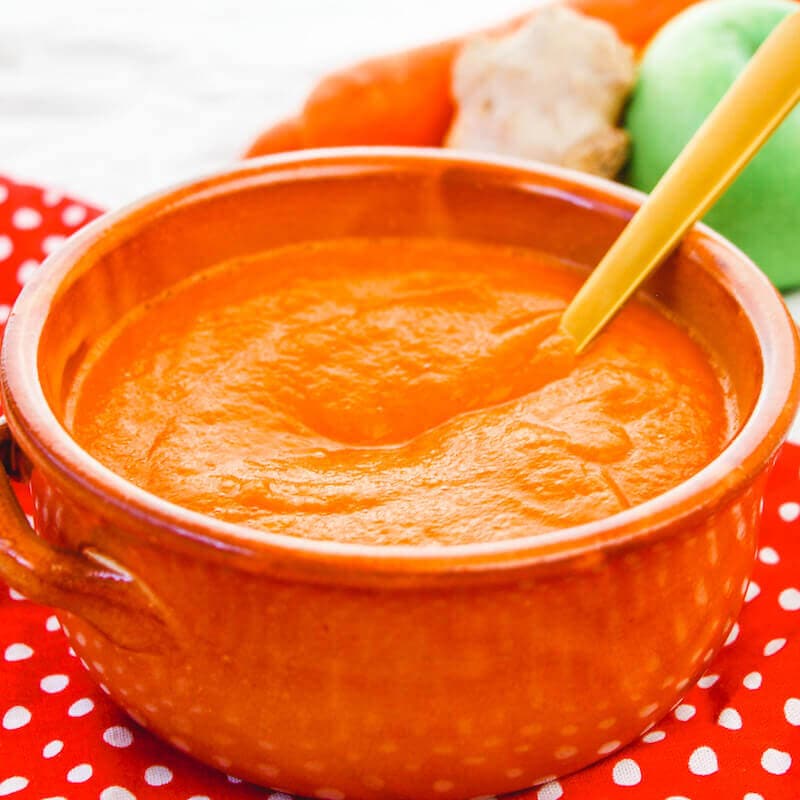 A stoneware bowl filled with carrot soup.