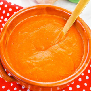 Overhead shot of roasted carrot soup on top of a red polka dot place mat.