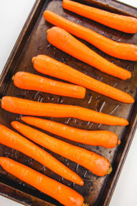 Peeled carrots on a cookie sheet and drizzled with oil.