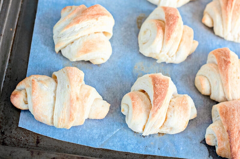 Freshly baked crescent rolls on a cookie sheet.