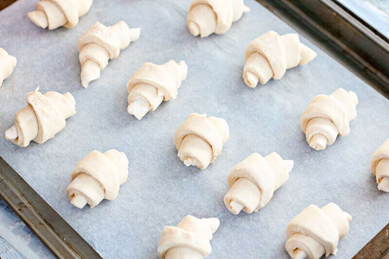 Dough rolled into crescents and placed on a parchment-lined baking sheet.