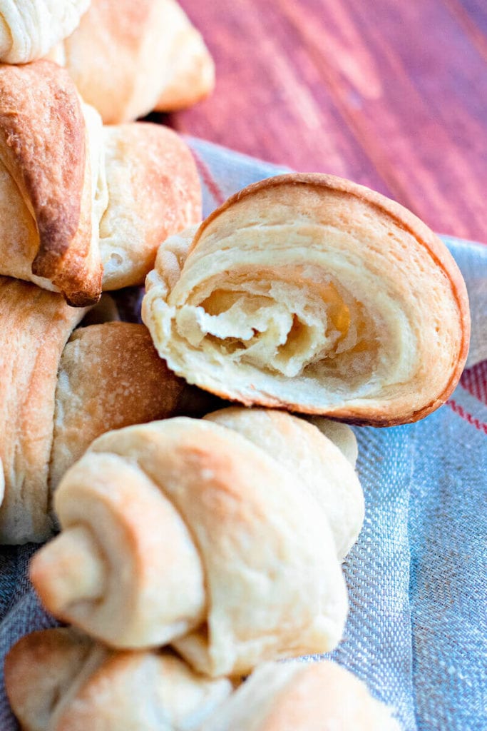 Close up of a crescent roll cut in half, showing it's flakey inside.