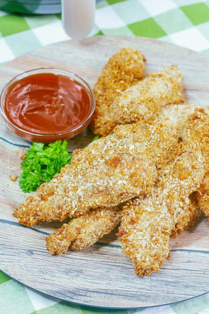 Air fried chicken strips on a green and white gingham tablelcloth.