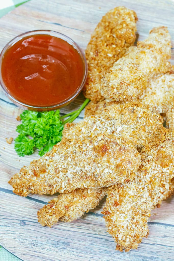 Close up of chicken tenders on a wooden plate.