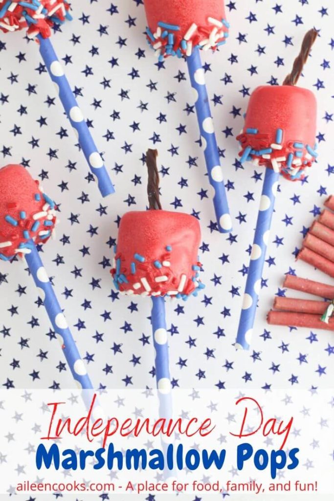 Five marshmallow pops decorated to look like firecrackers with the words "Independence Day Marshmallow Pops" in red and blue lettering.