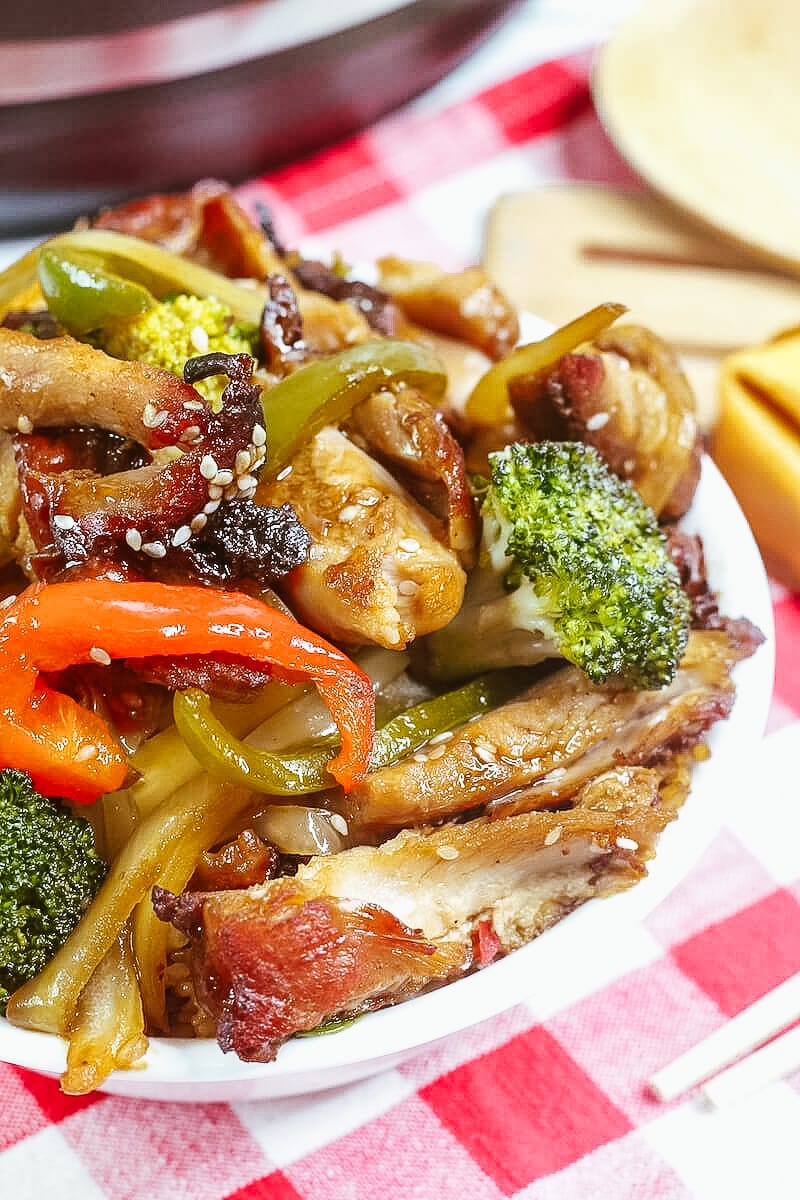 Overhead shot of honey garlic chicken with bell peppers in a white bowl.